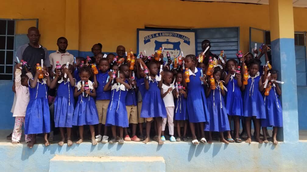 A group of children dressed in blue and white uniforms standing in front of a yellow and blue wall.