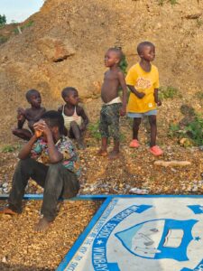 Children sitting on and standing on a hill