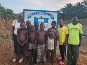 A group of children and adults standing in front of a sign.